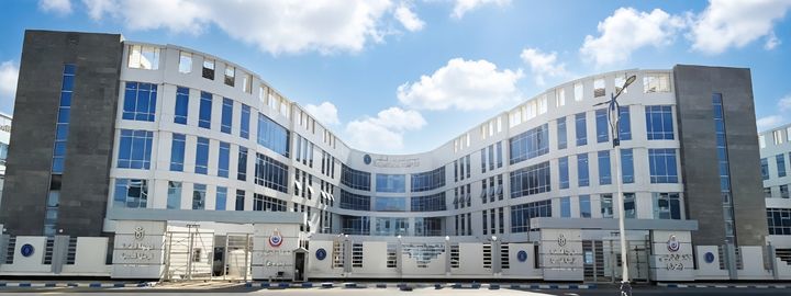 Front view of the Suez Medical Complex featuring a curved white-and-grey façade, large glass panels and a central entrance beneath a blue sky.
