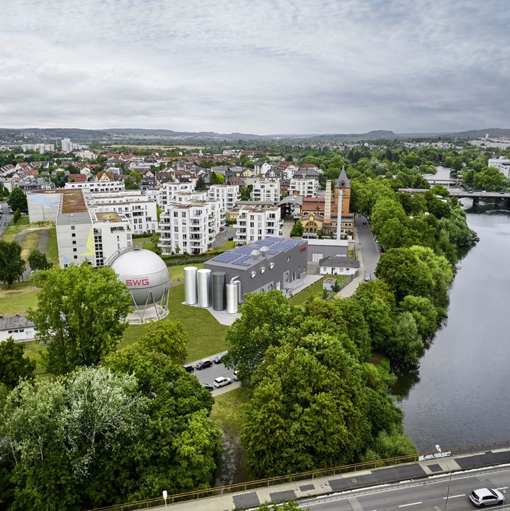 Luftbildmontage der geplanten PowerLahn-Anlage am Ufer der Lahn, umgeben von Bäumen und städtischer Bebauung in Gießen.