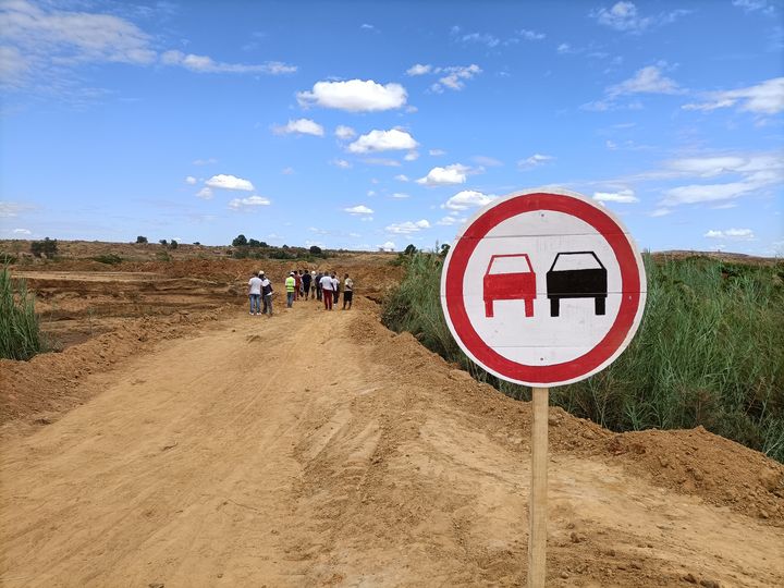 A group of people at the end of a rural road in construction.